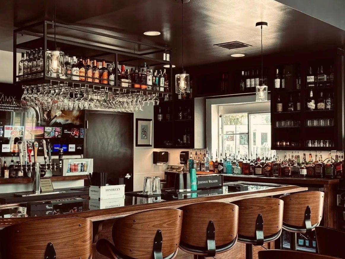 Palomino Cigar Lounge bar with walnut stools, beer taps, and a hanging rack of liquor bottles and glassware